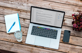 Laptop on desk with coffee and pen