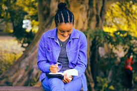 Woman writing in journal outside