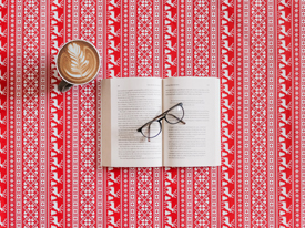 Open book with glasses on top, next to a latte