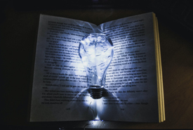 Open book in the dark with cracked lightbulb