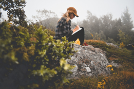 Woman outdoors writing in journal 