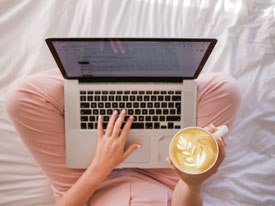 Person with laptop in lap and holding a latte